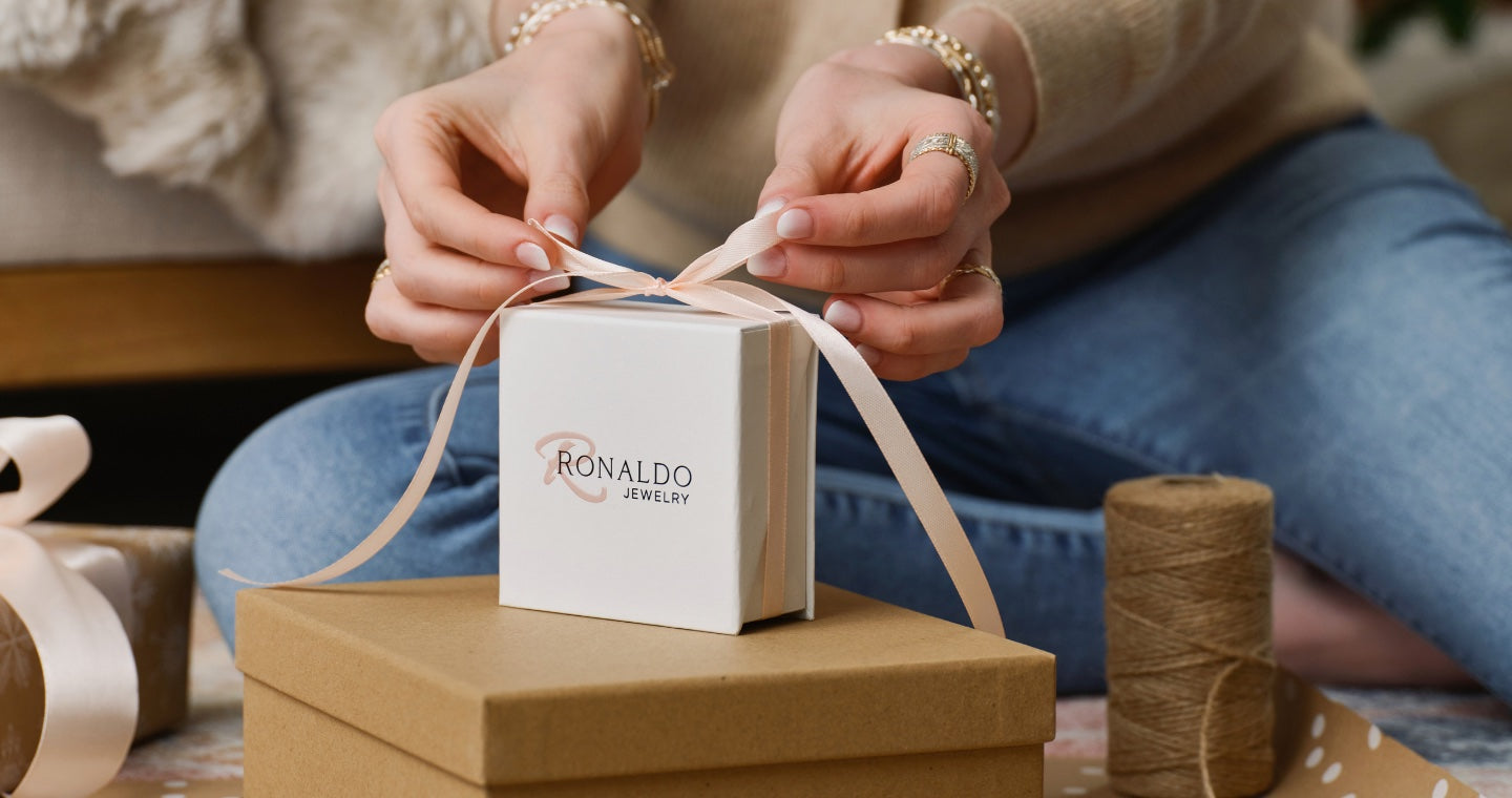 Hands tying a ribbon on a Ronaldo Jewelry gift box